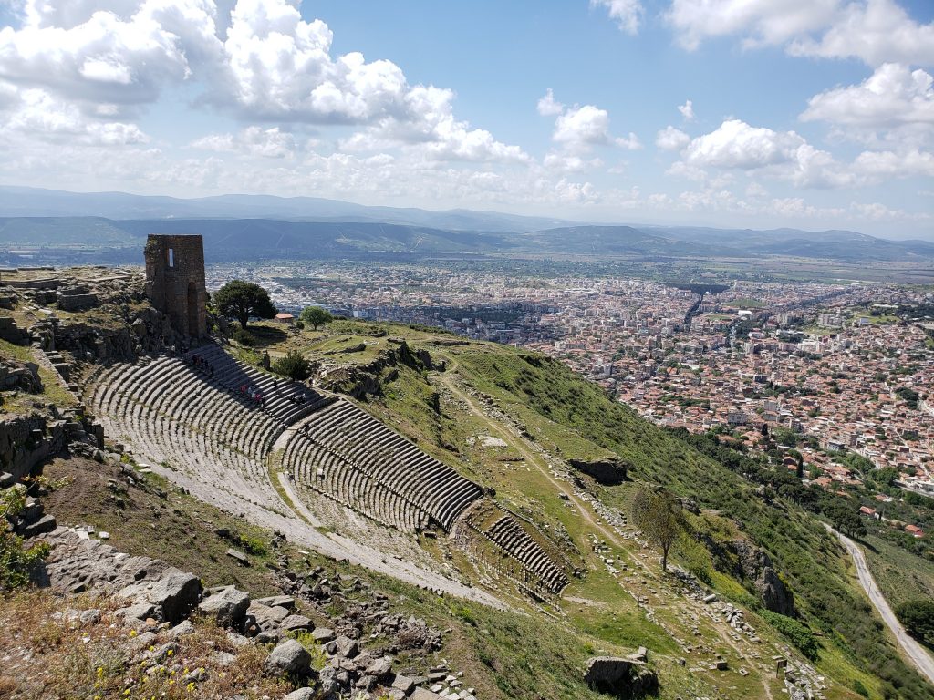 View over a steeply sloped theater built into the hillside, with views over the valley and city of Bergama far below