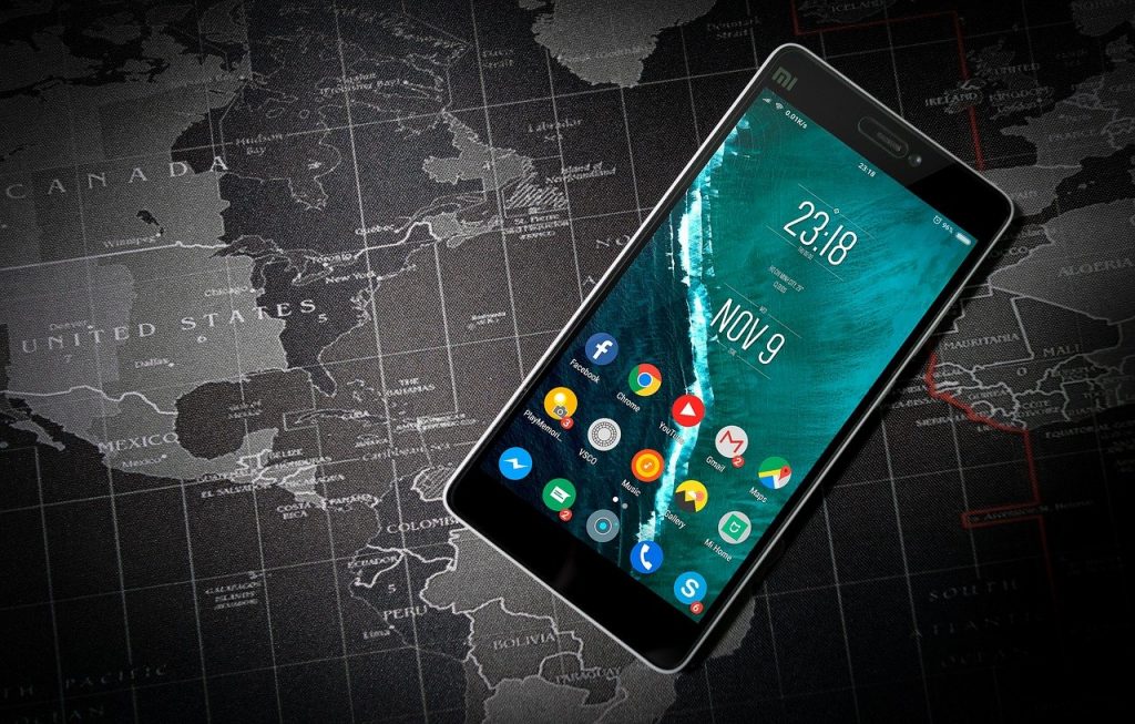 Image of an Android smartphone lying on a black and white map showing the Atlantic region from Canada and Scandinavia down to Paraguay and West Africa. Time zones are marked along with lines of longitude and latitude.