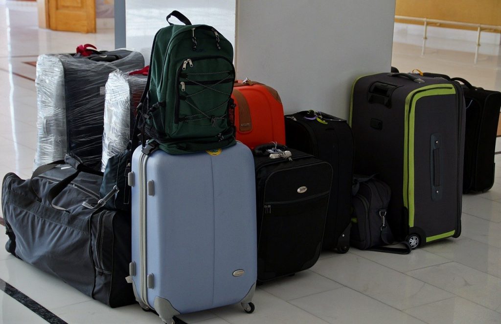 Suitcases and backpacks of various sizes sit piled up around a pillar.