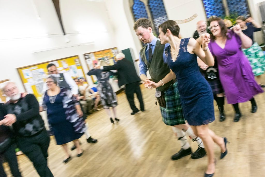 Ceilidh dancers blur as they move quickly!
